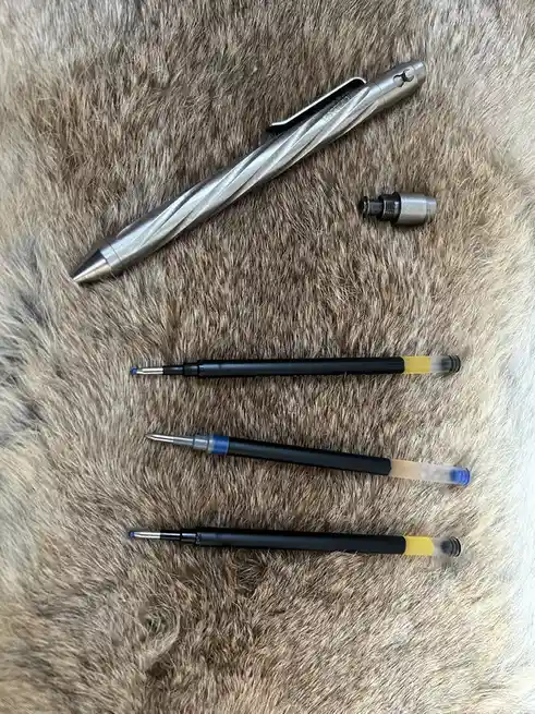 A silver, twisty mechanical pencil lies next to its cap on a furry brown surface, with three standard black ballpoint pens…