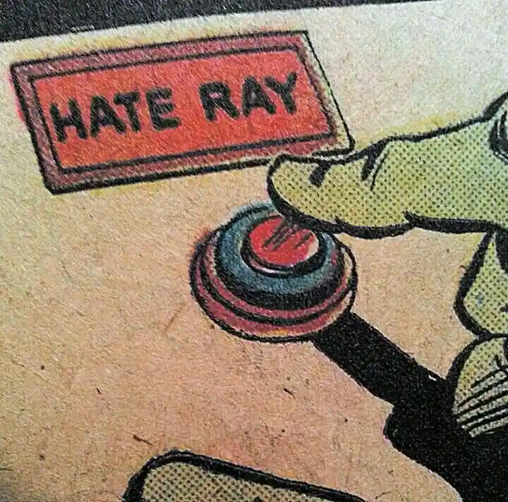 A vintage comic book panel shows a cartoonish green-skinned hand pressing a large red button labeled 'HATE RAY'. The artwork…
