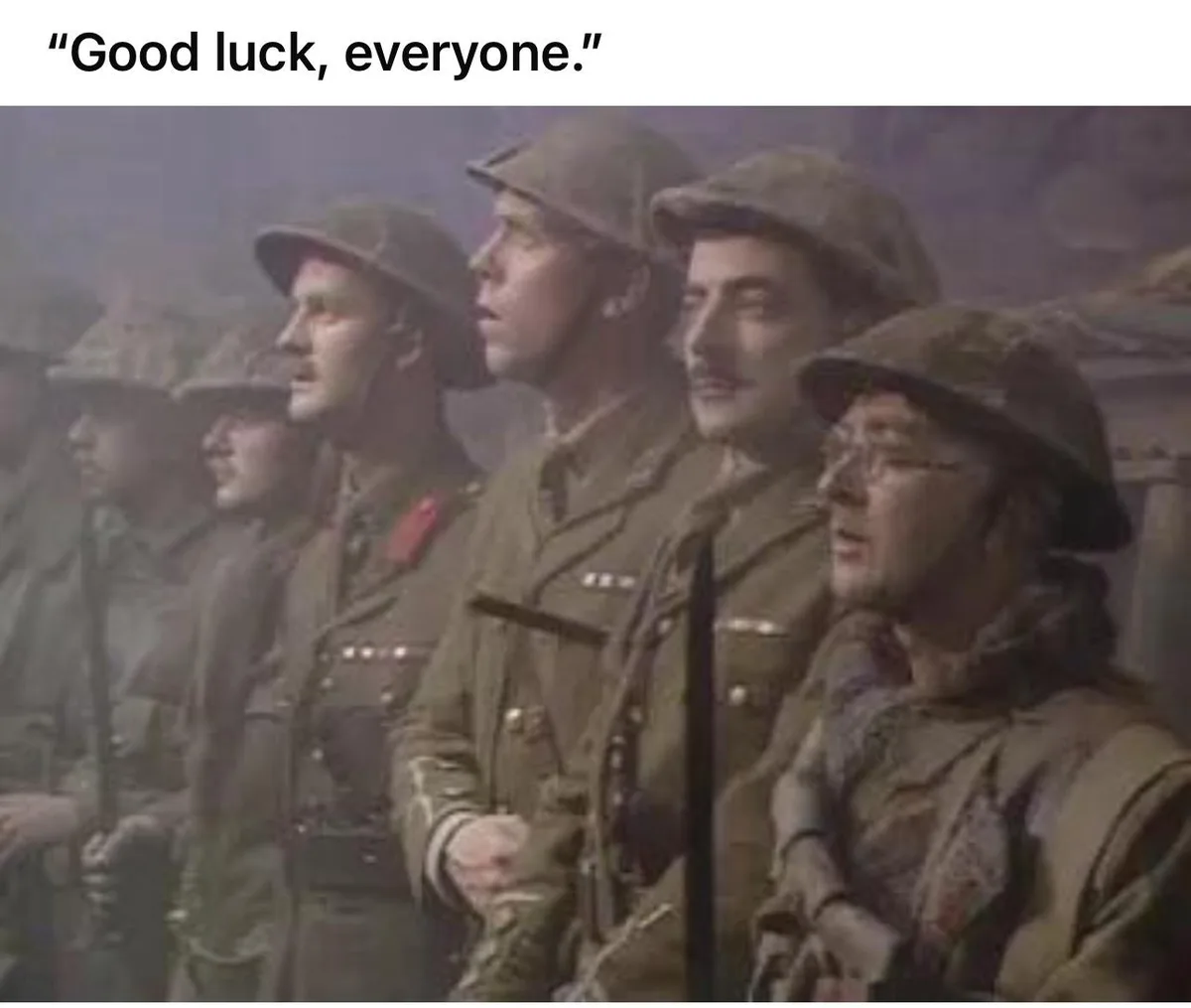 A historical photograph shows a line of soldiers in uniform and helmets, standing at attention in a foggy or smoky…