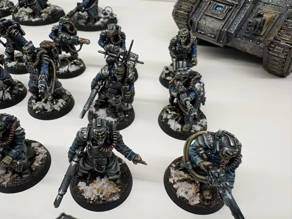 A collection of painted miniature sci-fi soldiers in heavy armor, some with skulls on helmets, standing on bases with…