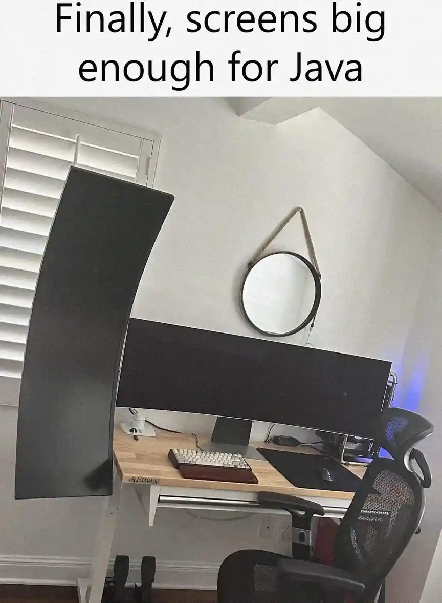 An office setup with two large, curved computer monitors mounted on a desk, one standing vertically and the other…