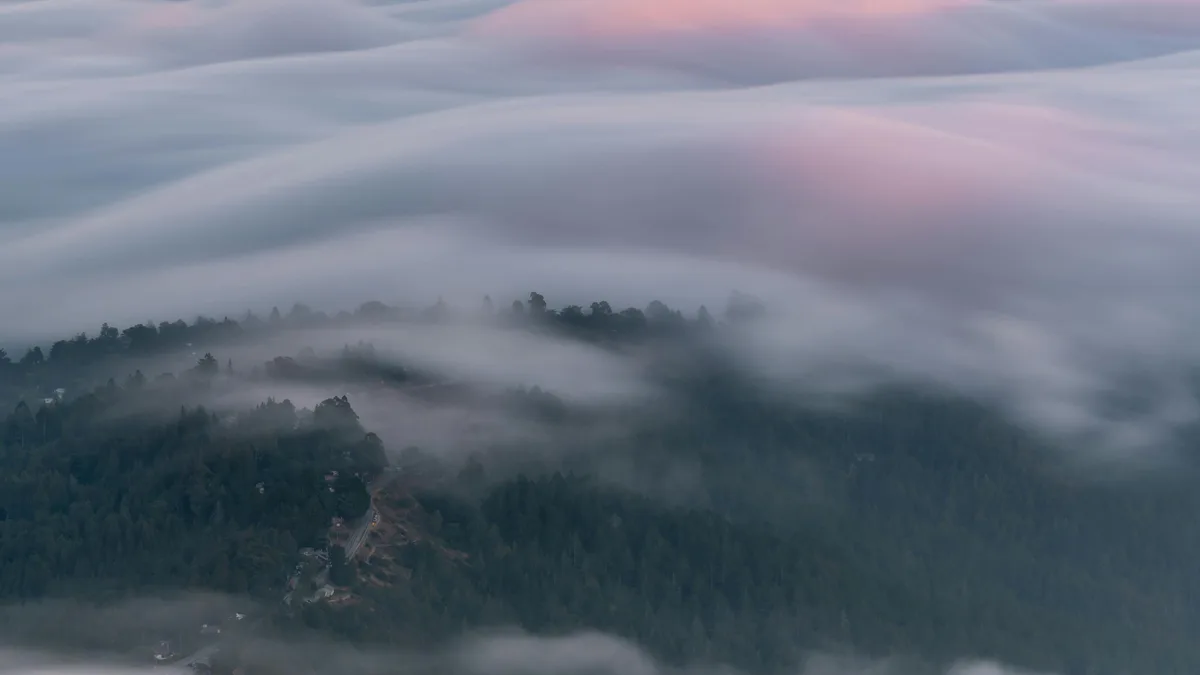 Golden light creeps over the mist-shrouded peaks, awakening the mountains to a new day. Soft wisps of fog cling to rugged…