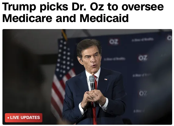 A man in a dark suit and red tie holds a microphone while standing in front of an American flag and a backdrop with…