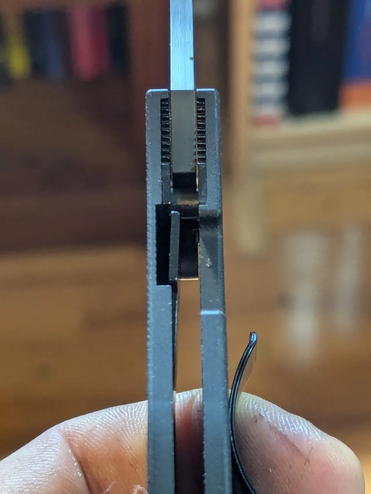 A close-up photo shows a hand holding a knife with its blade partially open, revealing the internal mechanism. The blade is…