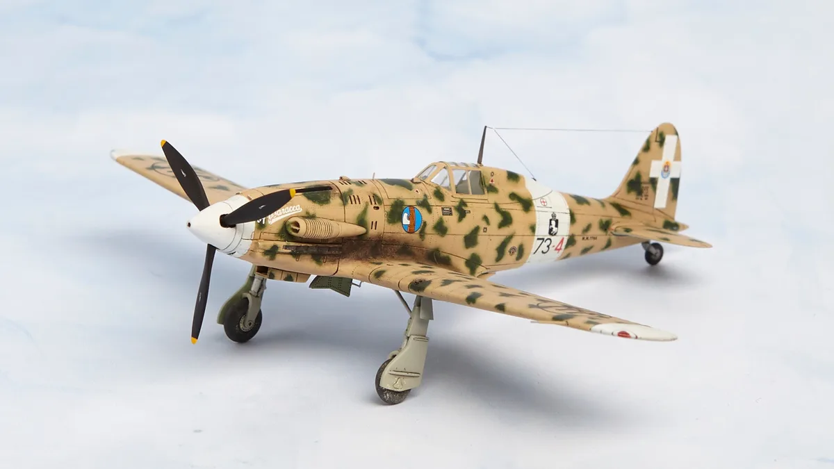 A detailed scale model of a military fighter plane with desert camouflage paint, featuring markings including the number…