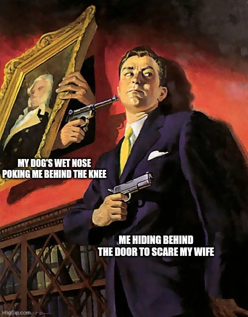 A man in a dark suit and yellow tie holds two pistols, one pointed at his head and one at his side, while standing behind a…