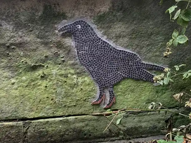 A mosaic artwork of a bird on a mossy stone wall, with its feet depicted as high-heeled shoes. The overlaid text reads 'i'm…