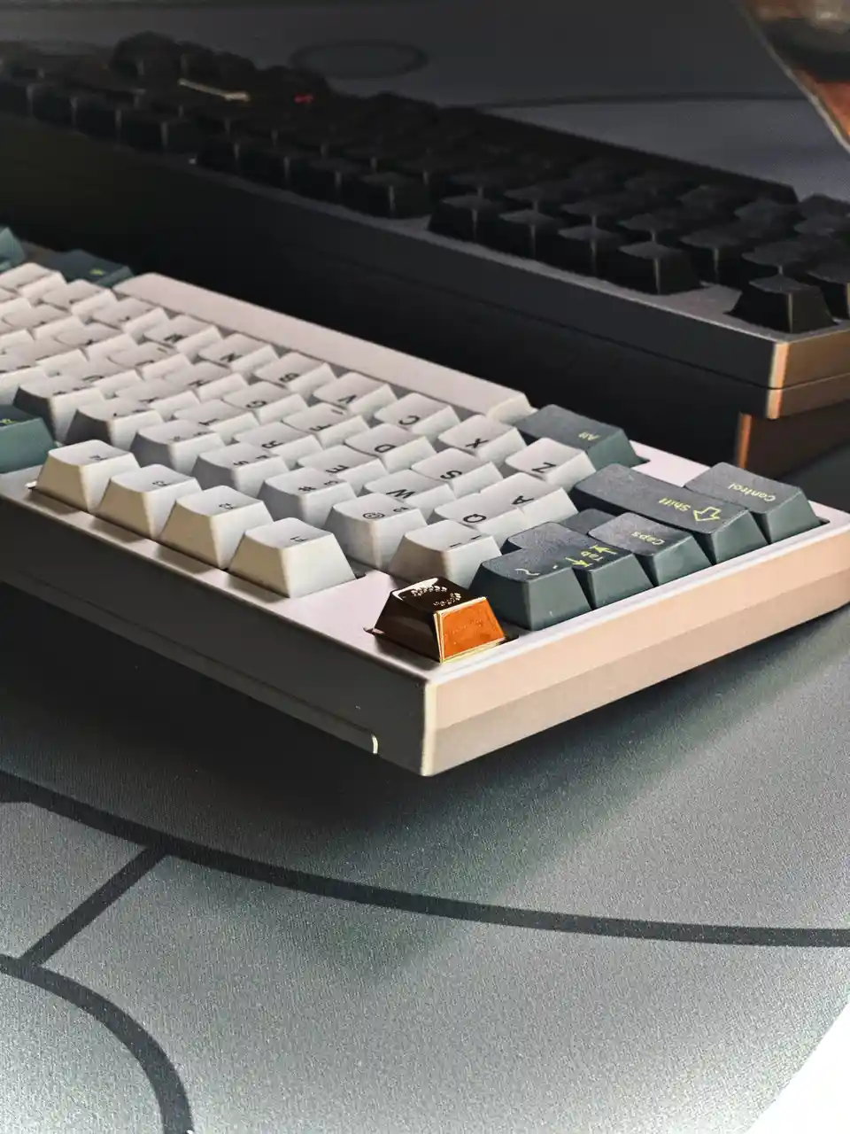 A close-up photo shows a mechanical keyboard with a single, ornate gold keycap on the bottom-left corner, contrasting with…