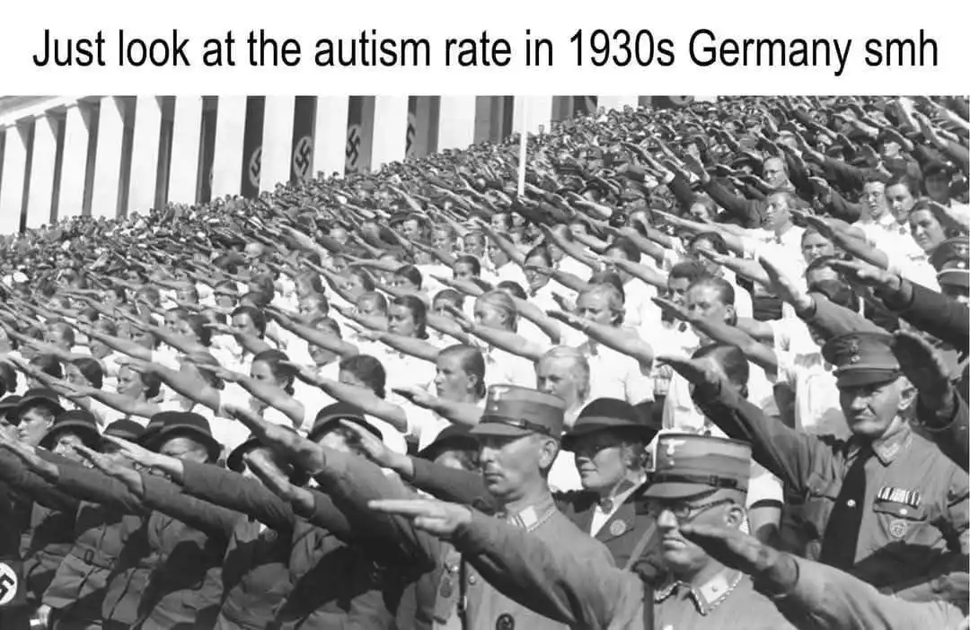A black-and-white historical photograph shows a massive crowd of people, including men, women, and children, performing the…