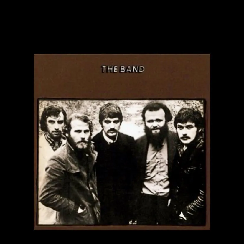 A black and white photo of five men, presumably a band, standing together with serious expressions. The text 'THE BAND' is…