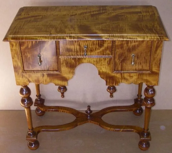 a polished wooden console table with three drawers, ornate turned legs, and a decorative scalloped apron, overlaid with the…