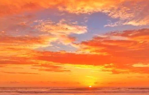 A vibrant sunset over the ocean with orange, red, and purple clouds, overlaid with the text 'i'm not lazy, i'm in…