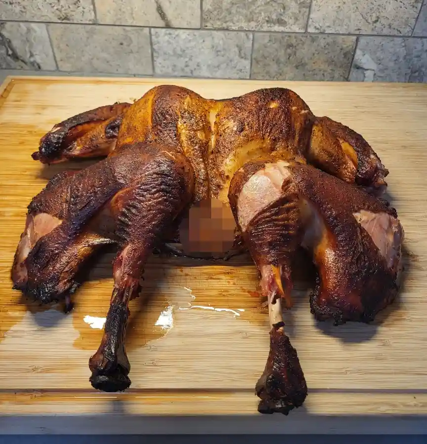 A roasted bird, likely duck or goose, sits on a wooden cutting board with its body and limbs arranged to resemble a human…