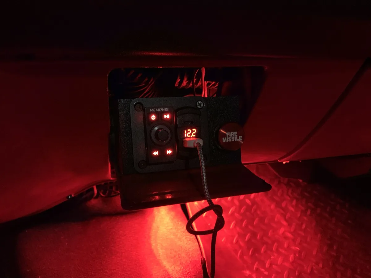 A close-up of a red-lit control panel inside a vehicle, featuring a 'MEMPHIS' branded unit with illuminated buttons and a…