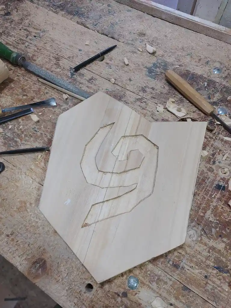 A piece of light-colored wood with a partially carved logo resembling the Oklahoma City Thunder basketball team's emblem…