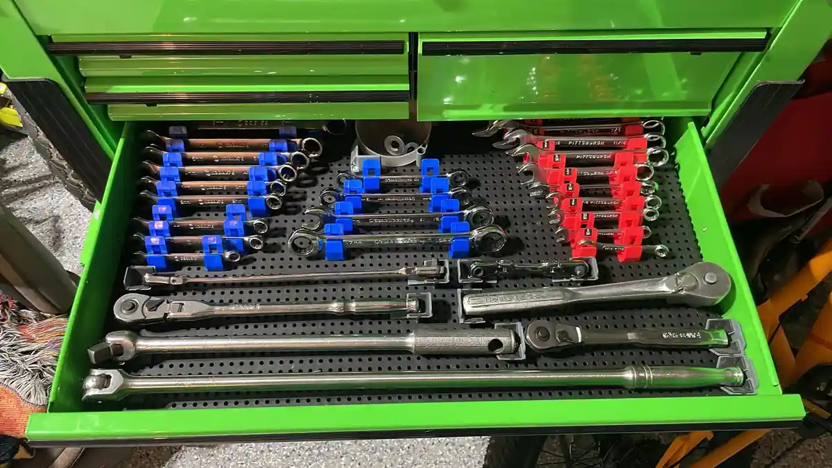 A bright green tool chest drawer is open, revealing an organized collection of wrenches and ratchets neatly arranged in…