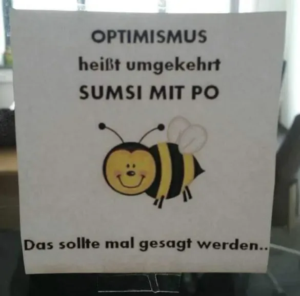 A white paper sign displays a cartoon bee with a smiling face and black-and-yellow stripes. The text above the bee reads…
