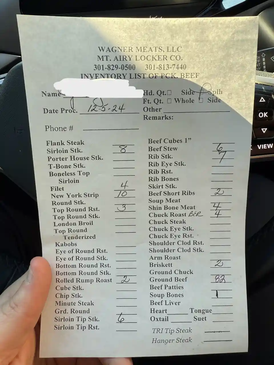 A hand holds a printed inventory list from Wagner Meats, LLC, detailing beef cuts with handwritten quantities. The list…