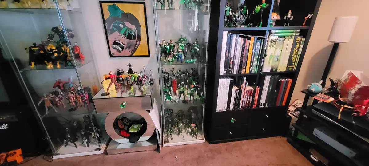A room filled with extensive Green Lantern-themed collectibles, including numerous action figures in glass display cases, a…