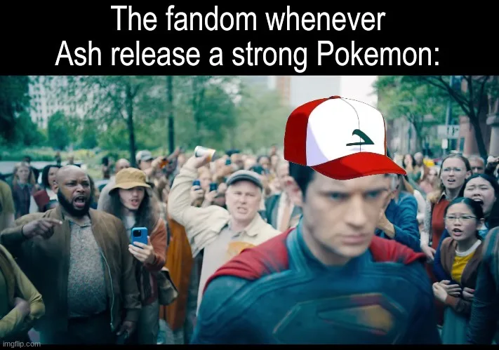 A man in a Superman costume wearing a red and white Ash Ketchum baseball cap stands in front of a crowd of people who are…