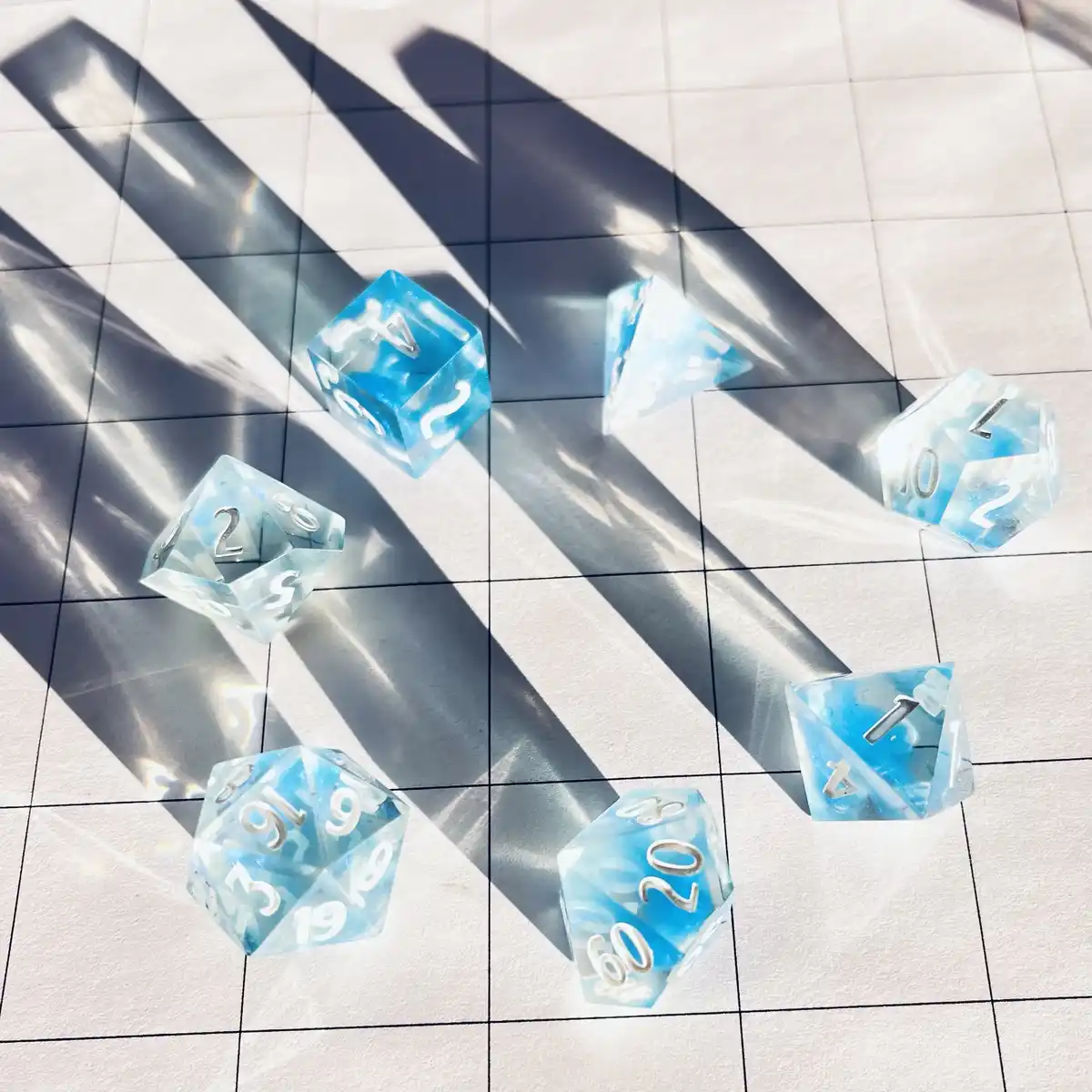 Several translucent blue and white polyhedral dice are scattered on a tiled floor, illuminated by strong diagonal sunlight…