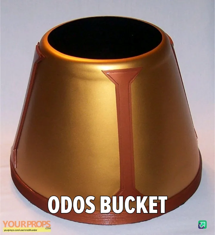 A golden, cone-shaped bucket with a brown rim and a brown 'I' symbol on its side, overlaid with the text 'ODOS BUCKET'. The…