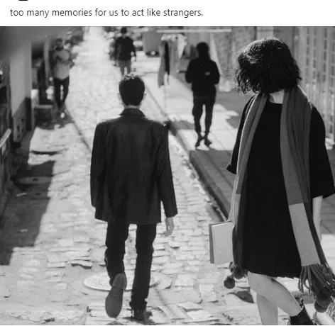 A black-and-white photo shows a man and woman walking away from each other down a cobblestone alley, both seen from behind…