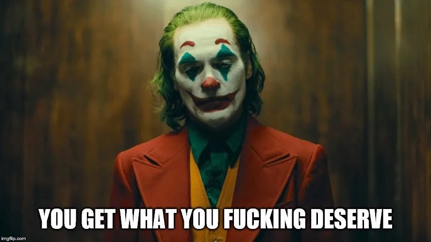 The image shows the character Joker from the movie 'Joker' (2019), wearing his iconic red suit, green shirt, and yellow…