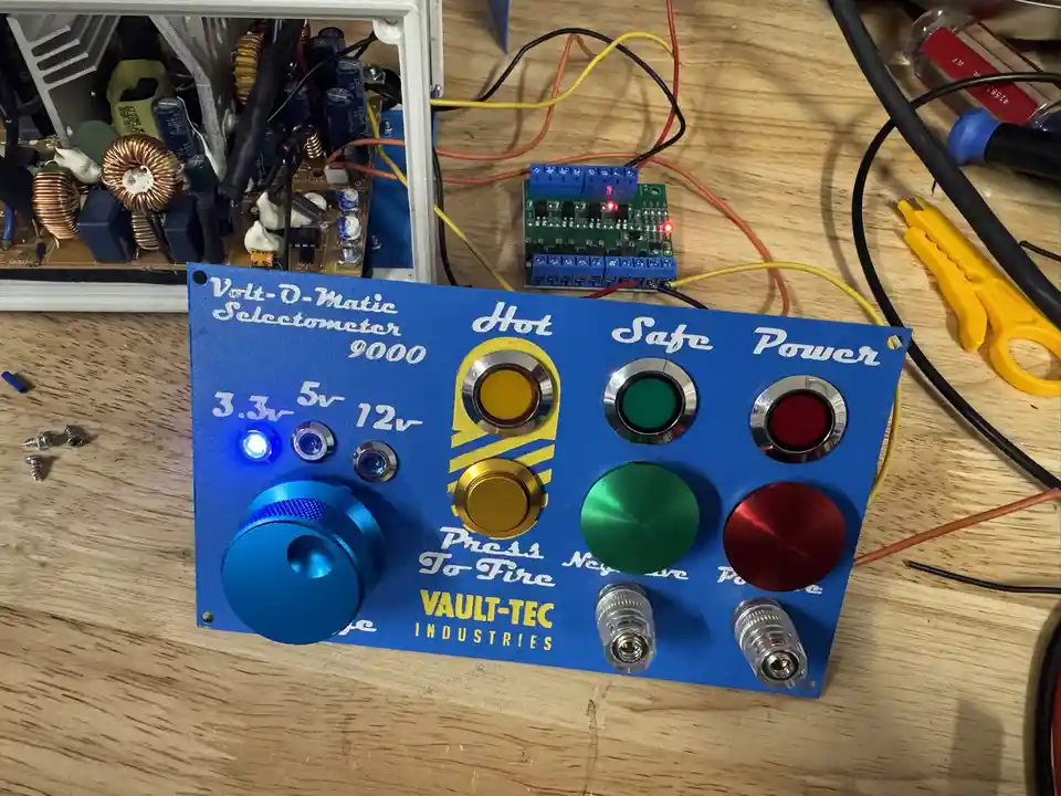 A blue DIY electronic control panel labeled 'Volt-O-Matic Selectometer 9000' and 'VAULT-TEC INDUSTRIES' sits on a wooden…