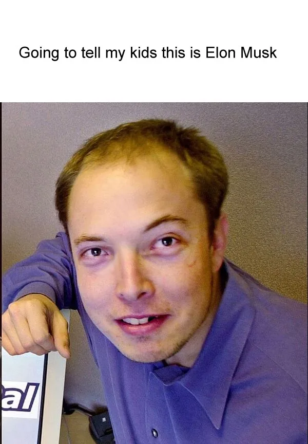 A close-up photo of a man with light brown hair, wearing a purple collared shirt, leaning forward with his right hand…