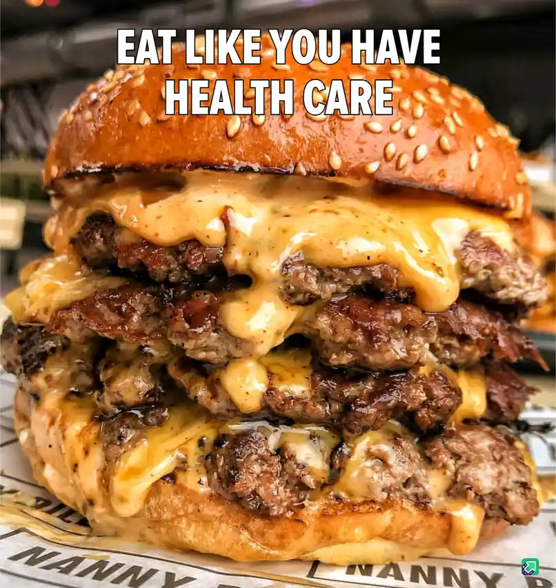 A close-up photo of an extremely large, multi-layered cheeseburger with multiple beef patties and melted cheese oozing…