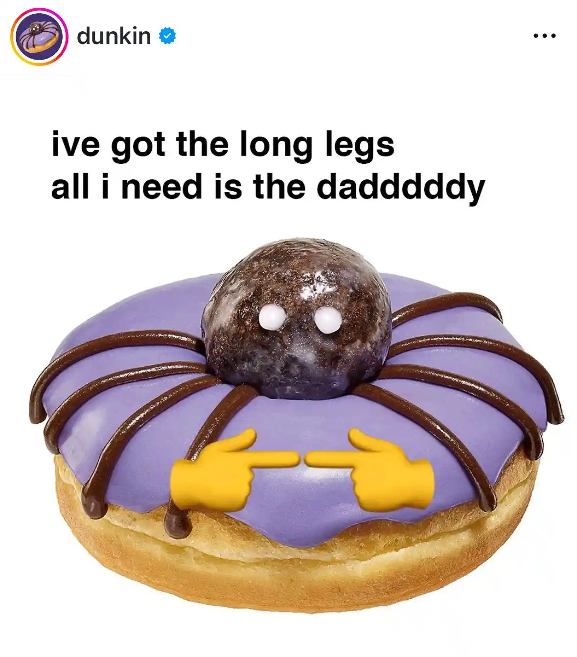 A purple-frosted Dunkin' donut is decorated to look like a spider, with chocolate drizzle legs, white candy eyes, and two…