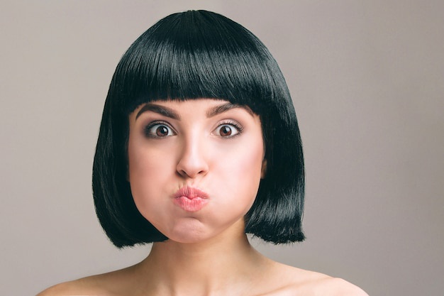 a woman with a black bob haircut and bangs makes a pouting, exaggeratedly surprised face. The overlaid text reads 'i'm not…