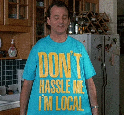 A six-panel image collage shows a man in a bright blue t-shirt with yellow text reading 'DON'T HASSLE ME I'M LOCAL'. He is…