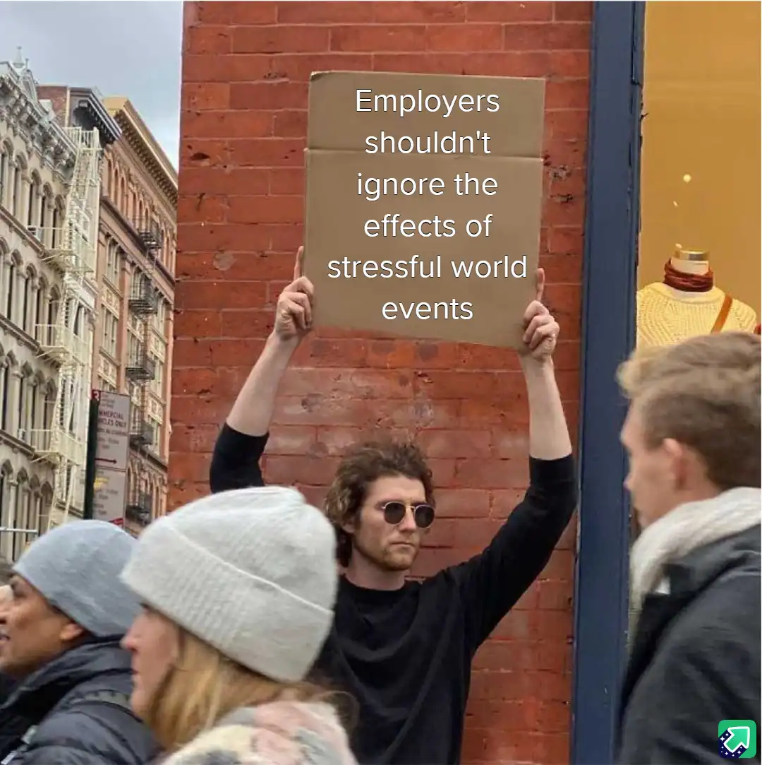 A man with curly hair and sunglasses holds up a cardboard sign with white text that reads 'Employers shouldn't ignore the…