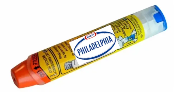 A tube of Kraft Philadelphia cream cheese is shown with a yellow and orange medical alert label overlaid on its side…