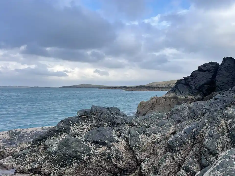 A scenic photo of a rocky coastline with blue water and cloudy skies, overlaid with the text 'i'm not lazy, i'm in…