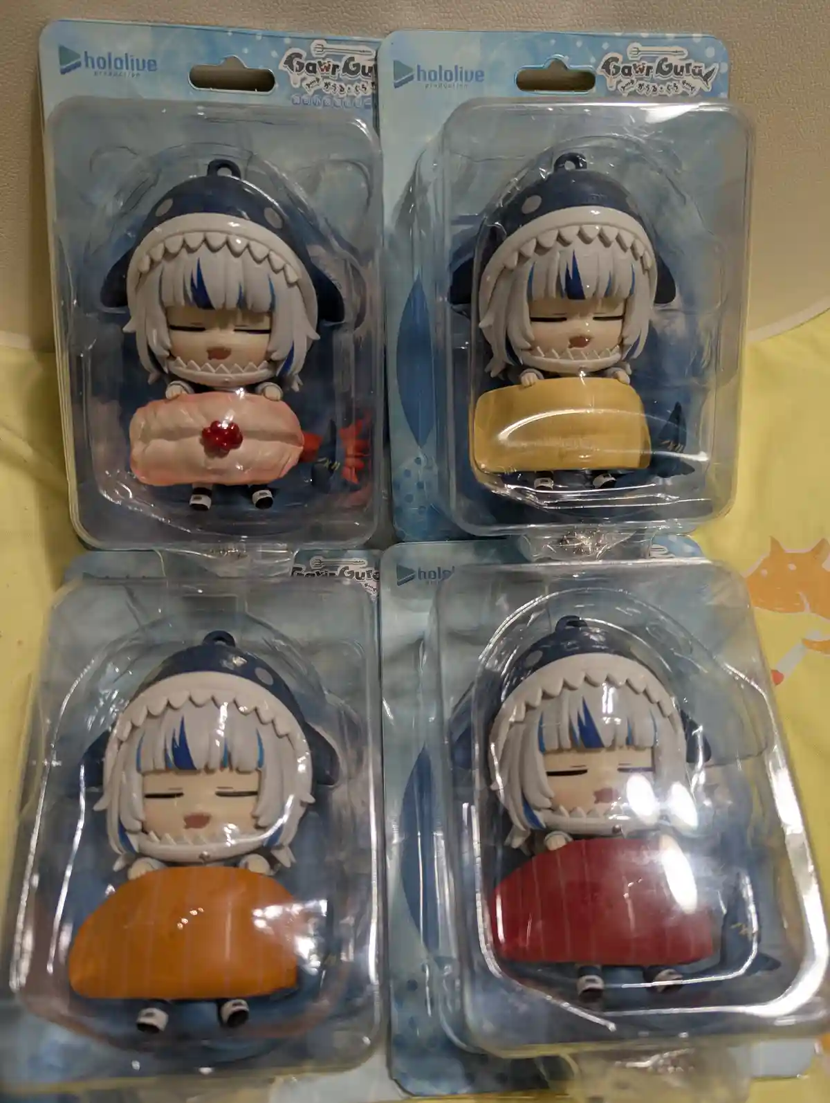 Four packaged hololive production 'Gawr Gura' keychain figures, each depicting the character in a shark-themed outfit…