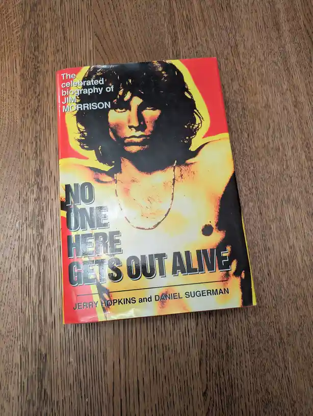 A book titled 'The celebrated biography of JIM MORRISON' by Jerry Hopkins and Daniel Sugerman, featuring a shirtless Jim…