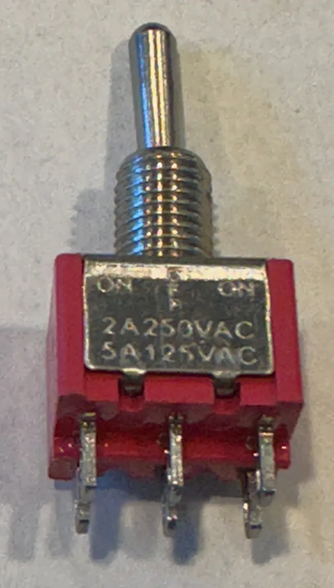 A close-up photo of a red toggle switch with a metal lever, showing its specifications: 'ON ON 2A250VAC 5A125VAC' engraved…