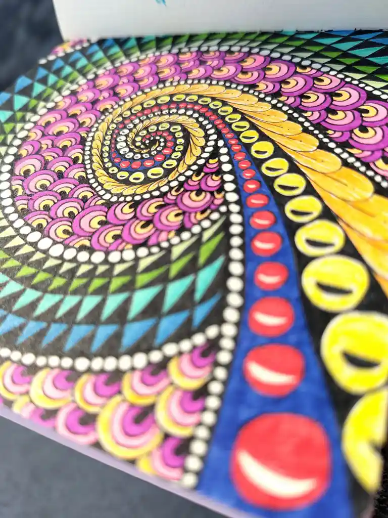 A close-up of a vibrant, intricate zentangle-style artwork featuring a swirling spiral pattern composed of colorful…
