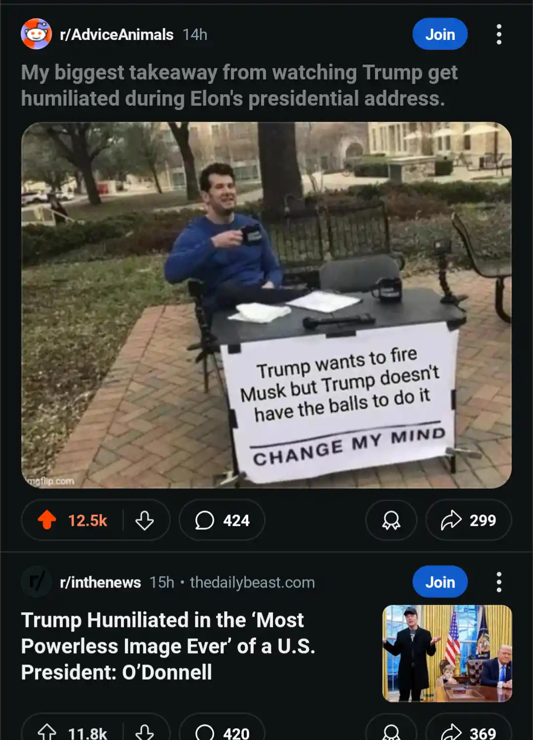 A man sits at an outdoor table holding a camera, with a sign in front of him that reads 'Trump wants to fire Musk but Trump…