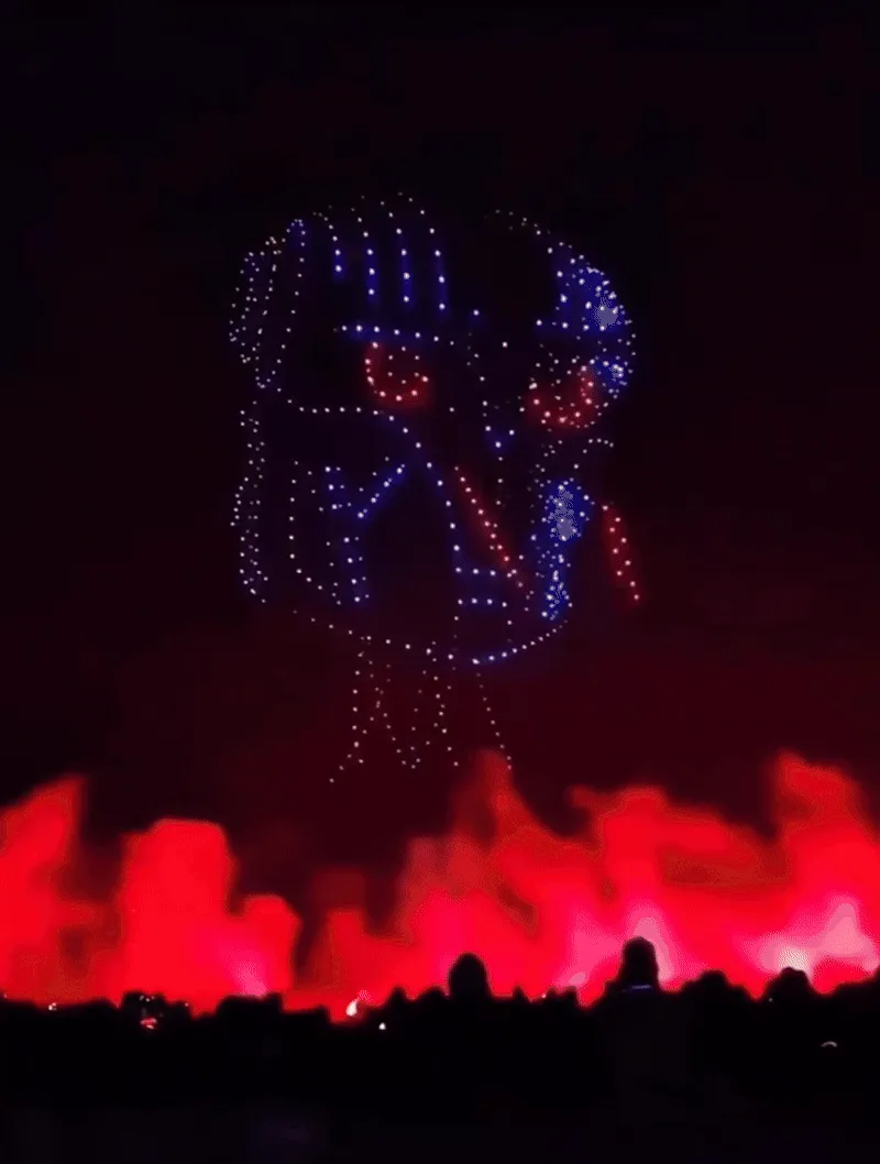 Three vertical panels show a drone formation shaped like a stylized face with glowing blue dots and red eyes, flying over a…