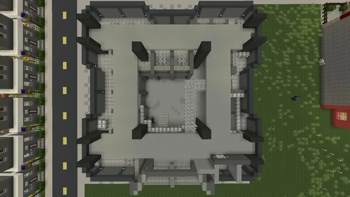 An overhead view of a Minecraft building with a complete floor plan but no roof, surrounded by grass, a road, and other…
