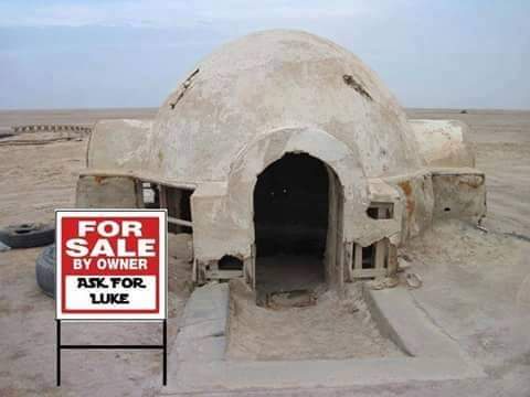 A weathered, dome-shaped structure resembling a Star Wars Mos Eisley cantina or a similar desert dwelling stands in a…