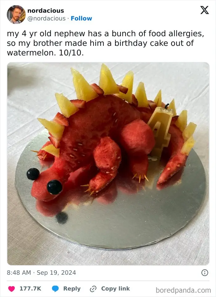 A watermelon has been carved into the shape of a dinosaur, with pineapple slices forming spikes along its back and…