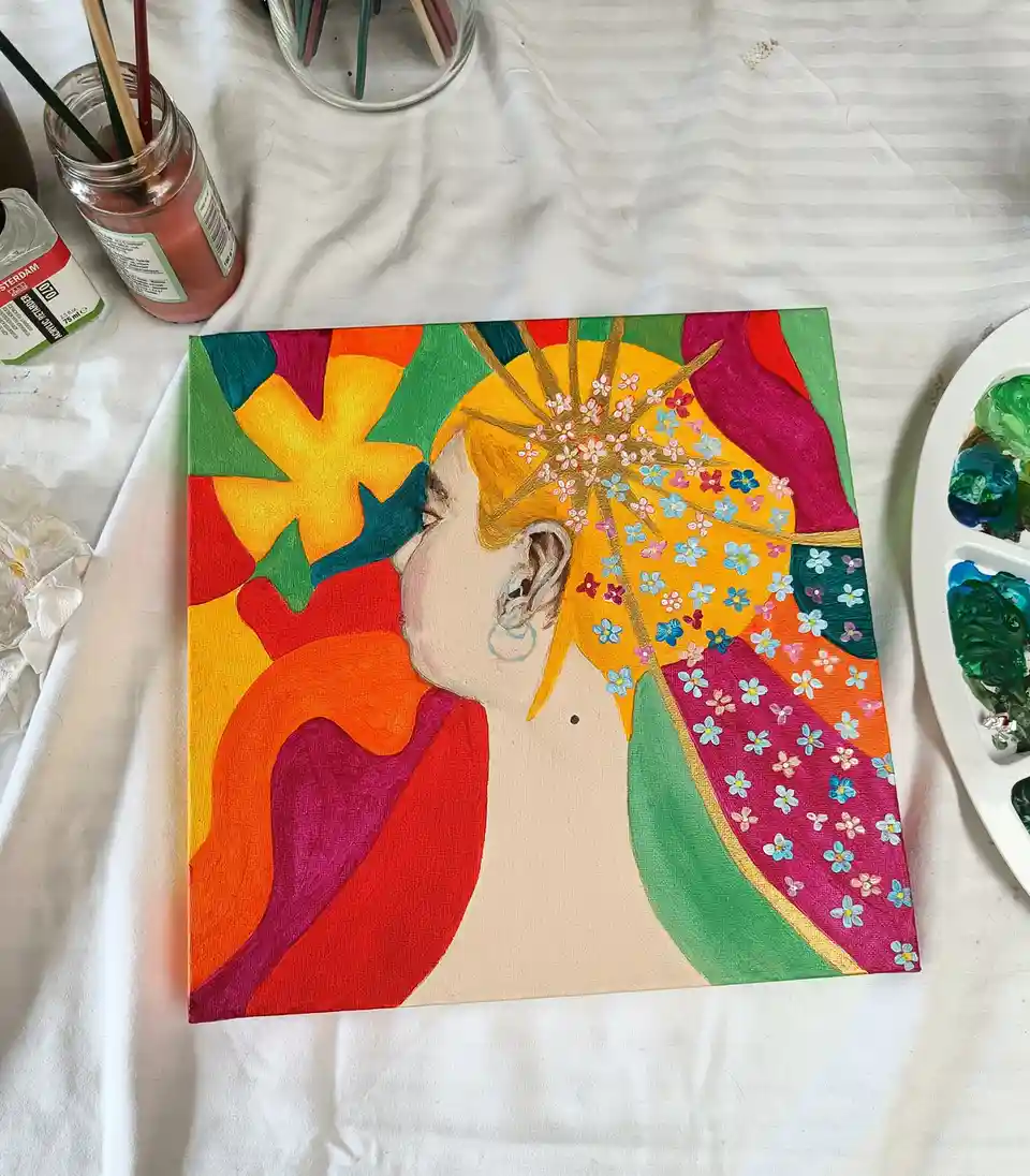 A colorful painting of a person's head and shoulders, with their hair replaced by a vibrant explosion of flowers and…