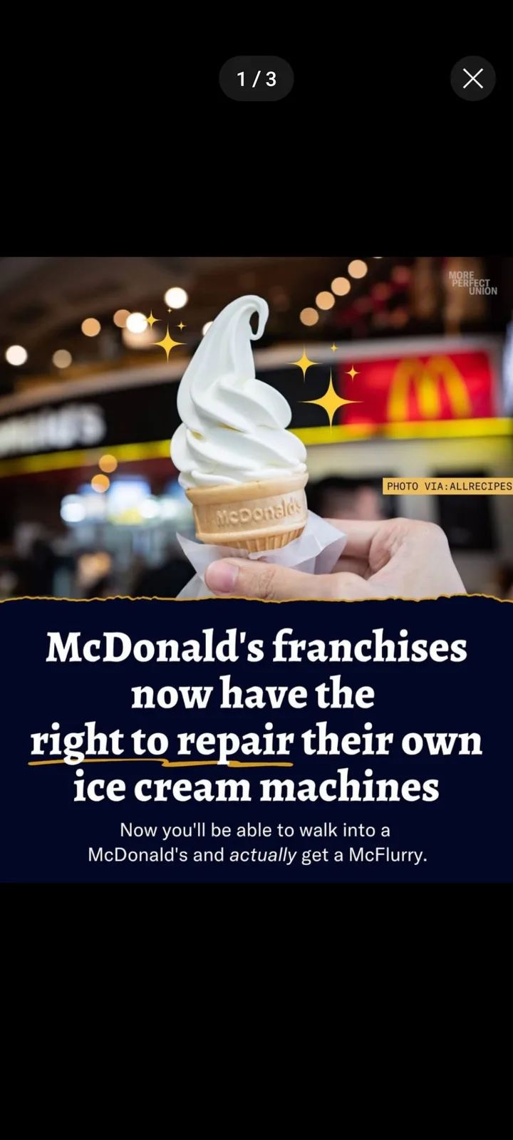 A hand holds a McDonald's branded soft-serve ice cream cone against a blurred background featuring the McDonald's logo…