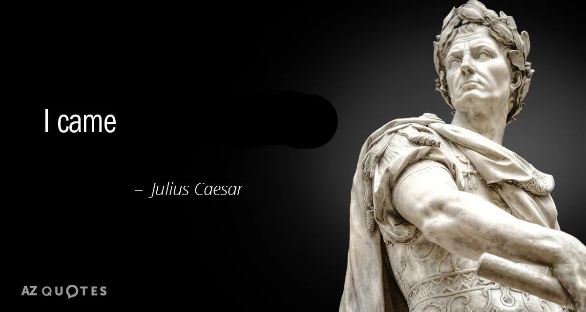 A black-and-white image shows a marble statue of Julius Caesar, wearing a laurel wreath and draped in a toga, looking upward…