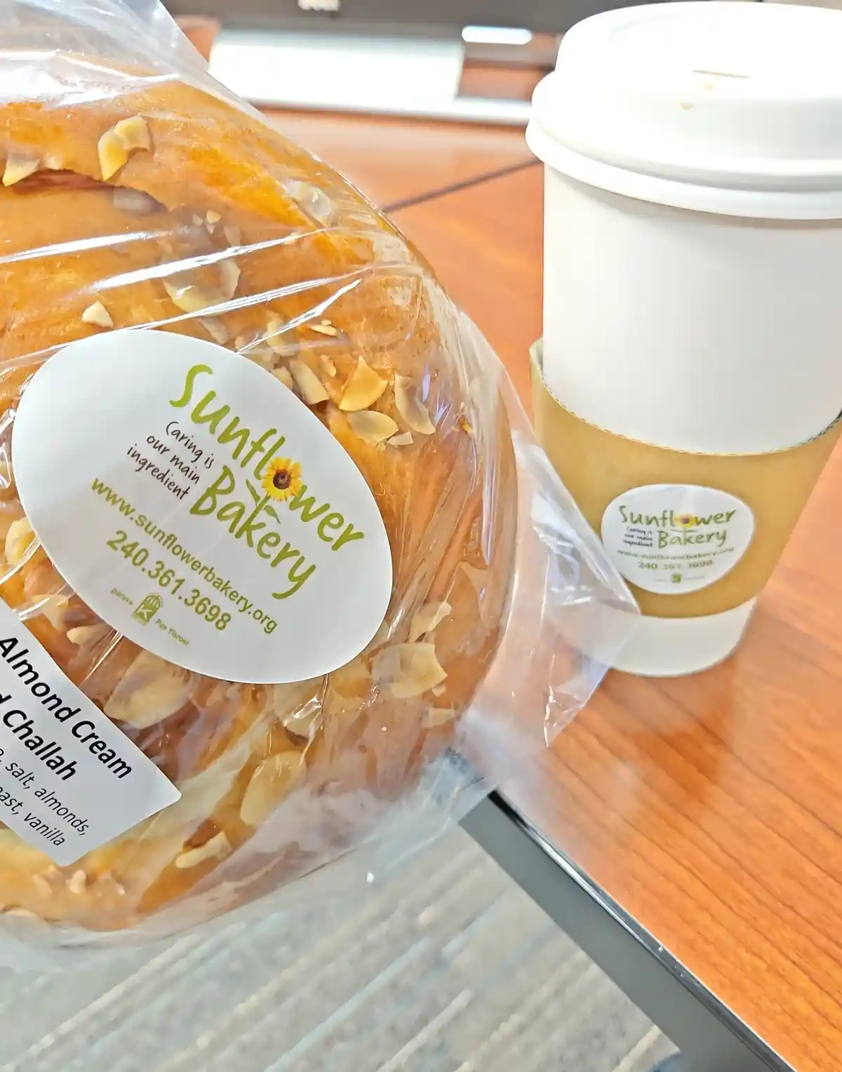 A close-up photo shows a packaged almond cream challah bread and a branded coffee cup from Sunflower Bakery, both featuring…